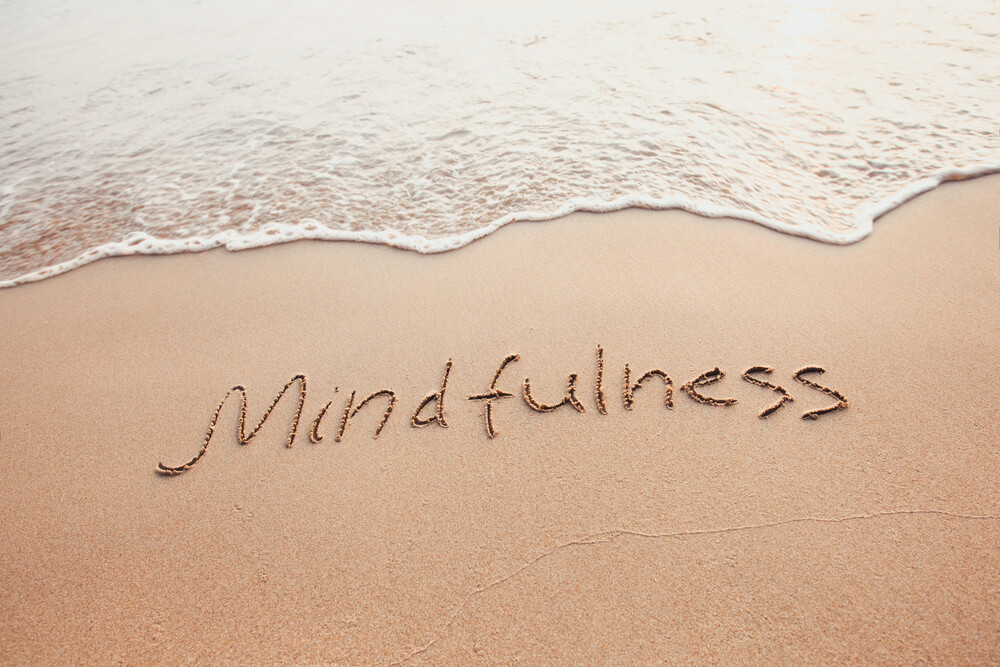 Mindfulness written in sand on shore