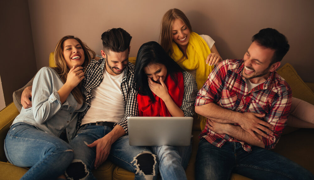 Friends laughing at something on a laptop